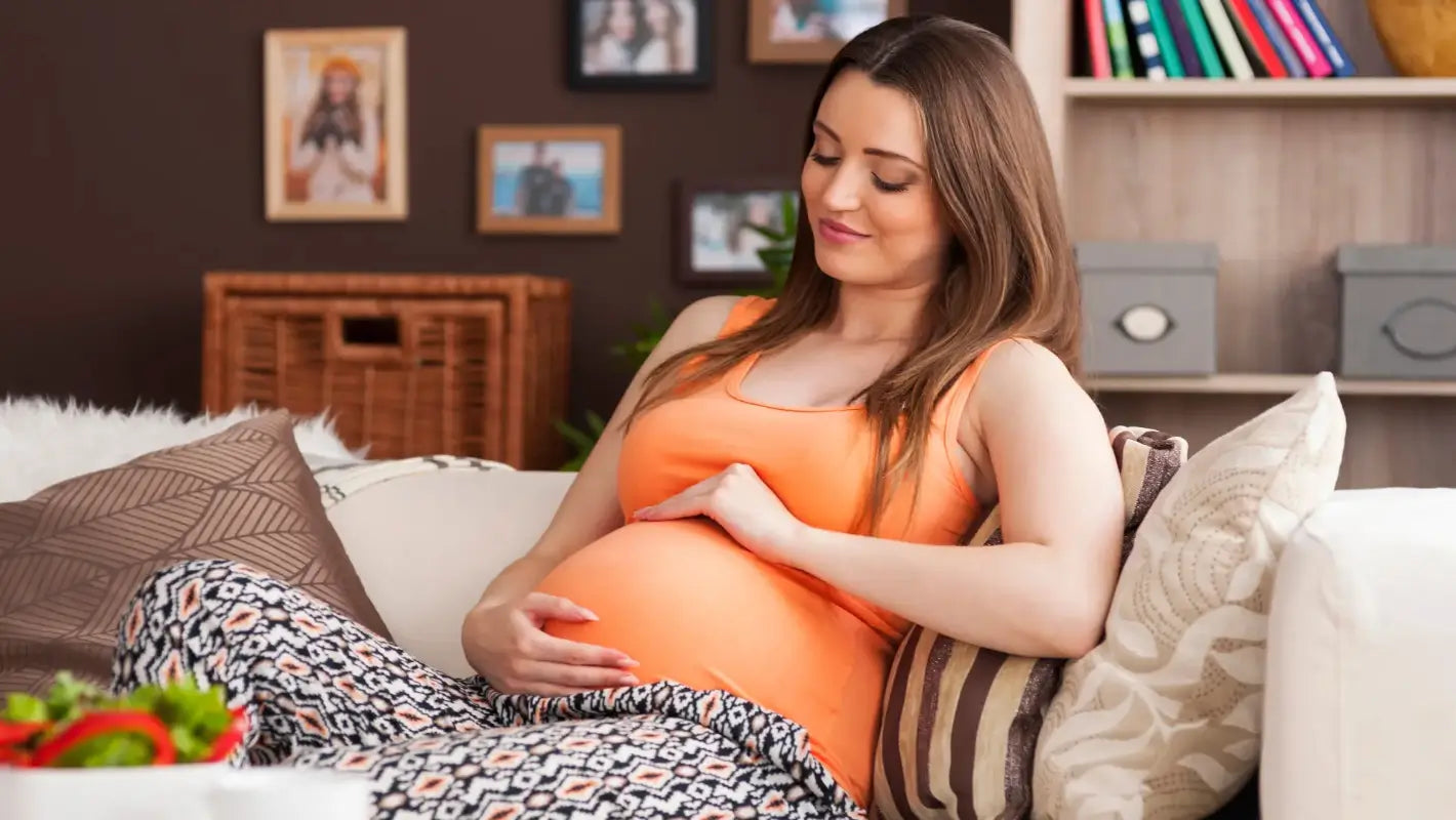 Zwangere vrouw comfortabel ontspannen, ondersteund door een full body Momie zwangerschapskussen voor ultieme rug, buik, en nek ondersteuning.